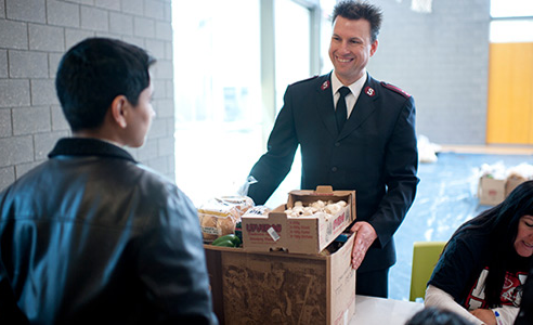 Salvation Army representative speaking with a community member while holding donated items.